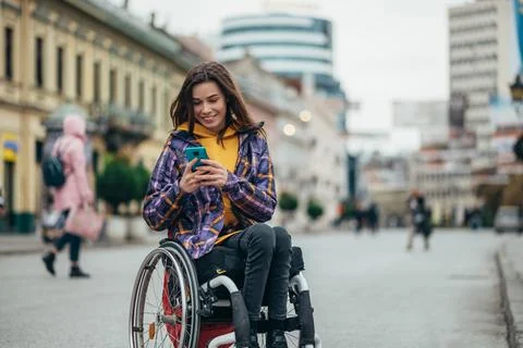 Woman with disability using a smartphone while out in the city Stock Photos