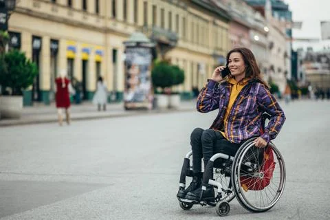 Woman with disability using a smartphone while out in the city Stock Photos