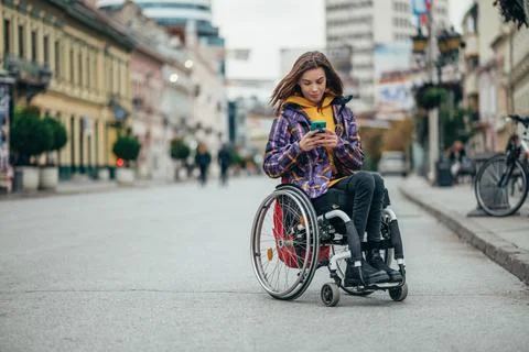 Woman with disability using a smartphone while out in the city Stock Photos