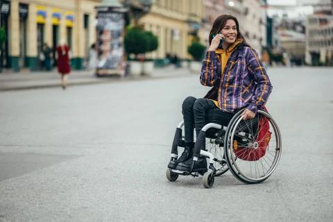 Woman with disability using a smartphone while out in the city Stock Photos