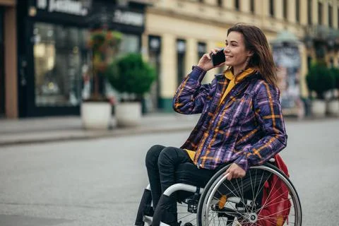 Woman with disability using a smartphone while out in the city Stock Photos