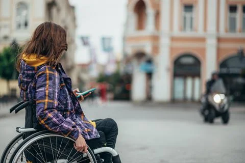 Woman with disability using a smartphone while out in the city Stock Photos