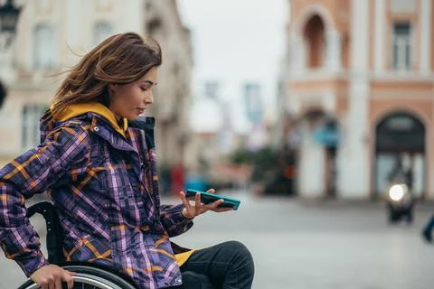 Woman with disability using a smartphone while out in the city Stock Photos