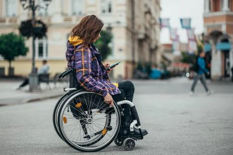Woman with disability using a smartphone while out in the city Stock Photos