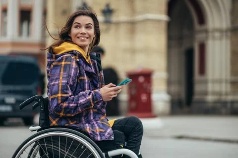 Woman with disability using a smartphone while out in the city Stock Photos