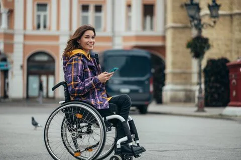 Woman with disability using a smartphone while out in the city Stock Photos