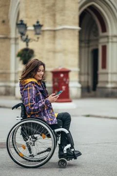 Woman with disability using a smartphone while out in the city Stock Photos