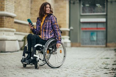 Woman with disability using a smartphone while out in the city Stock Photos