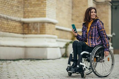 Woman with disability using a smartphone while out in the city Stock Photos