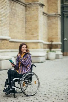 Woman with disability using a smartphone while out in the city Stock Photos