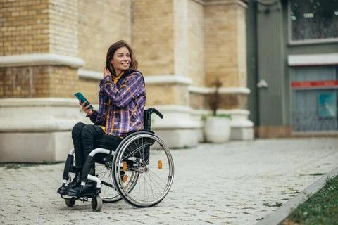 Woman with disability using a smartphone while out in the city Stock Photos
