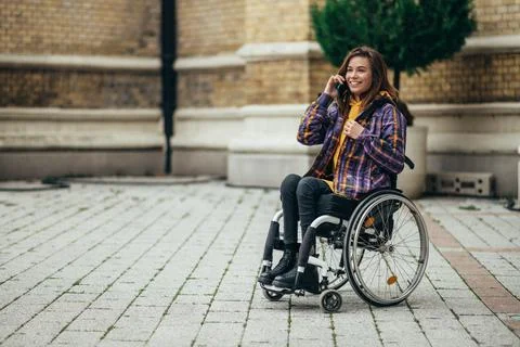 Woman with disability using a smartphone while out in the city Stock Photos