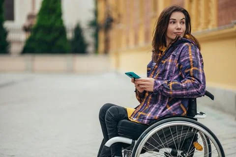 Woman with disability using a smartphone while out in the city Stock Photos