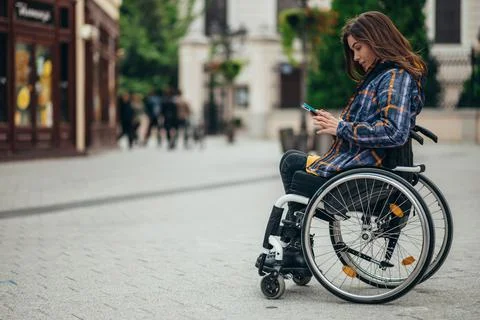 Woman with disability using a smartphone while out in the city Stock Photos