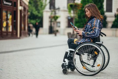 Woman with disability using a smartphone while out in the city Stock Photos