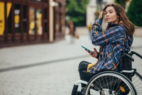 Woman with disability using a smartphone while out in the city Stock Photos