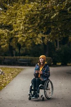 Woman with disability using a smartphone while out in the city park Stock Photos