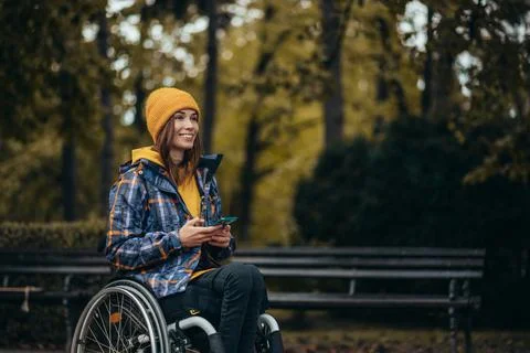 Woman with disability using a smartphone while out in the city park Stock Photos