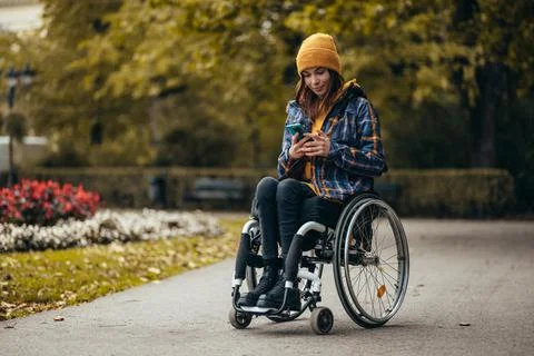 Woman with disability using a smartphone while out in the city park Stock Photos