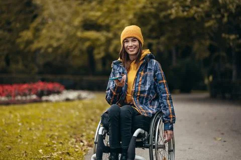 Woman with disability using a smartphone while out in the city park Stock Photos