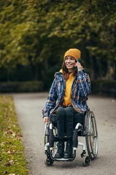 Woman with disability using a smartphone while out in the city park Stock Photos