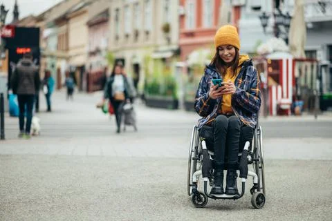 Woman with disability using a smartphone while out in the city Stock Photos