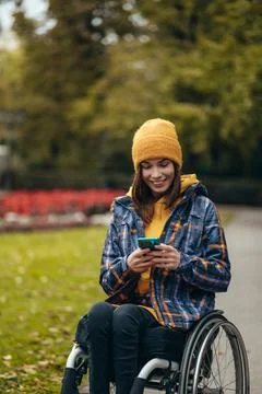 Woman with disability using a smartphone while out in the city park Stock Photos