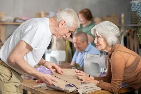 Woman discussing pattern with classmate during sewing course for older adults Stock Photos