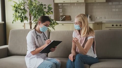 Woman doctor help middle aged woman during homecare medical visit with mask on Stock Footage 155291153