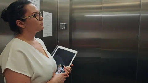 A woman with documents and a computer in her hands rides in the elevator Vídeos de archivo 246781445