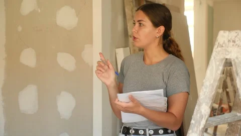 Woman with documents in her hands checks the quality of the completed repairs in Stock Footage 320449447