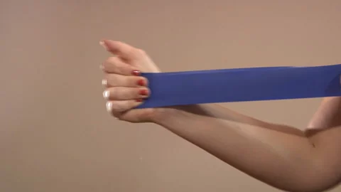 A woman does exercise by holding an elastic band in her hands. Physical activity Stock Footage 132658744