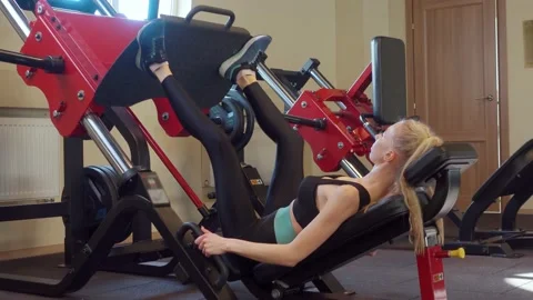 Woman does exercise for muscles of the buttocks and legs on the simulator. Gym Video stock 194357239