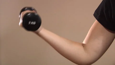 A woman does exercise while holding a 3kg weight in her hand Stock Footage 132659015