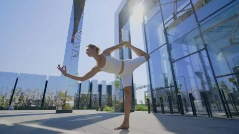 Woman does exercises practicing yoga by office building Stock Footage 272417813