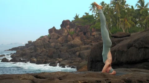 Woman does head stand on flat stone near ocean slow motion Vidéo 112267213