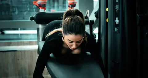 Woman does legs curl exercise in a fitness club. She is attractive and beautiful Stock Footage 141169932