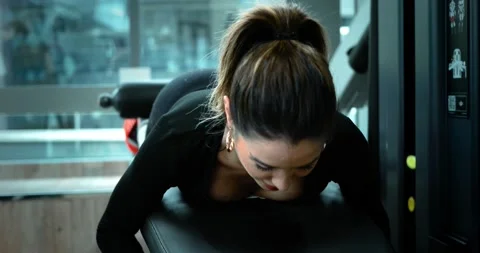 Woman does legs curl exercise in a fitness club. She is attractive and beautiful Stock Footage 141169935