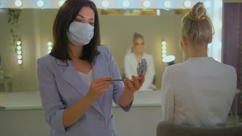 A woman does makeup in her Studio in a medical mask, Quarantine measures in a Stock Footage 136511285