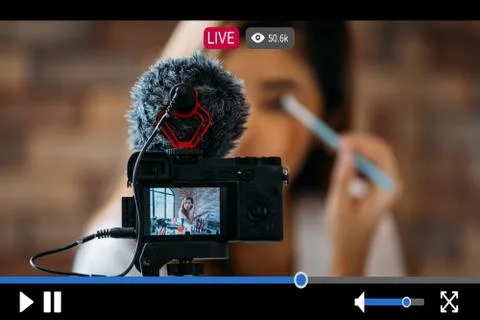 Woman does makeup while recording live stream with vide player interface Fotos de archivo