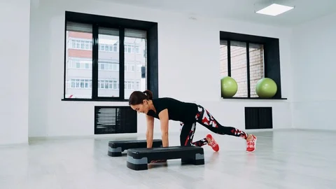 A woman does push-ups between step platforms and she does not succeed. The girl Stock Footage 113852030