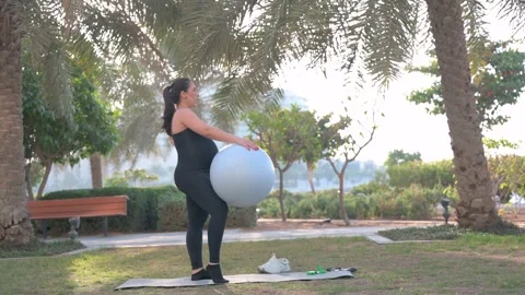 Woman Doing Balance Exercise With Stability Ball In Park For Outdoor Fitnes.. Stock Footage 328985753