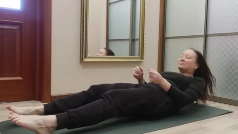 Woman doing corpse pose lying flat on green yoga mat relaxation exercise Vidéo 322519851