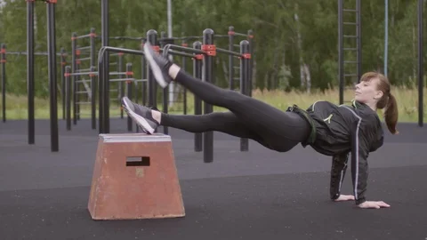 Woman Doing Evaluated Reverse Plank with Leg Raise at Outdoor Fitness Court Stock Footage 115026004