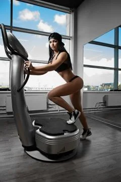 Woman doing exercise for the buttocks on the simulator Stock Photos
