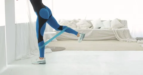 Woman is doing exercise for glutes using rubber band at home, legs closeup. Stock Footage 138090737