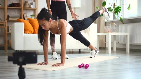 Woman doing exercise with personal trainer and making video for blog in Stock Footage 158360987