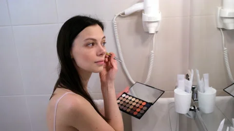Woman doing face contouring using coloufrul concealer palette looking at mirror. Stock Footage 238391339