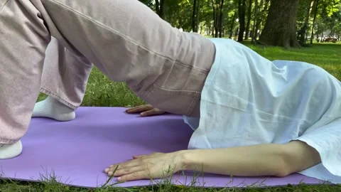 Woman doing glutes and hamstrings exercise on purple mat in park 動画素材 340149003