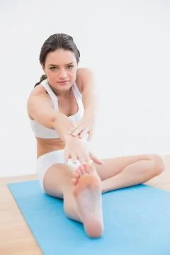 Woman doing the hamstring stretch on exercise mat Stock Photos